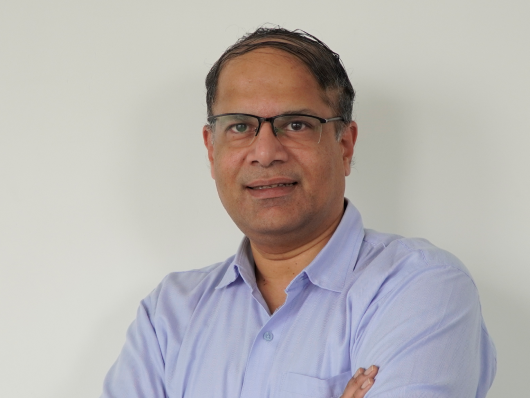 Man in blue shirt smiling with crossed arms.